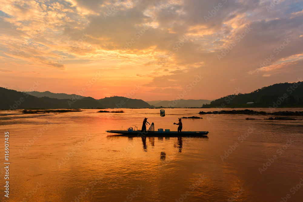 Fototapeta premium The suluate fisherman casting a net into the water during on sunset,Nongkhai Thailand
