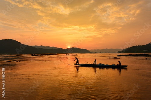 The suluate  fisherman casting a net into the water during on  sunset,Nongkhai Thailand © saravut