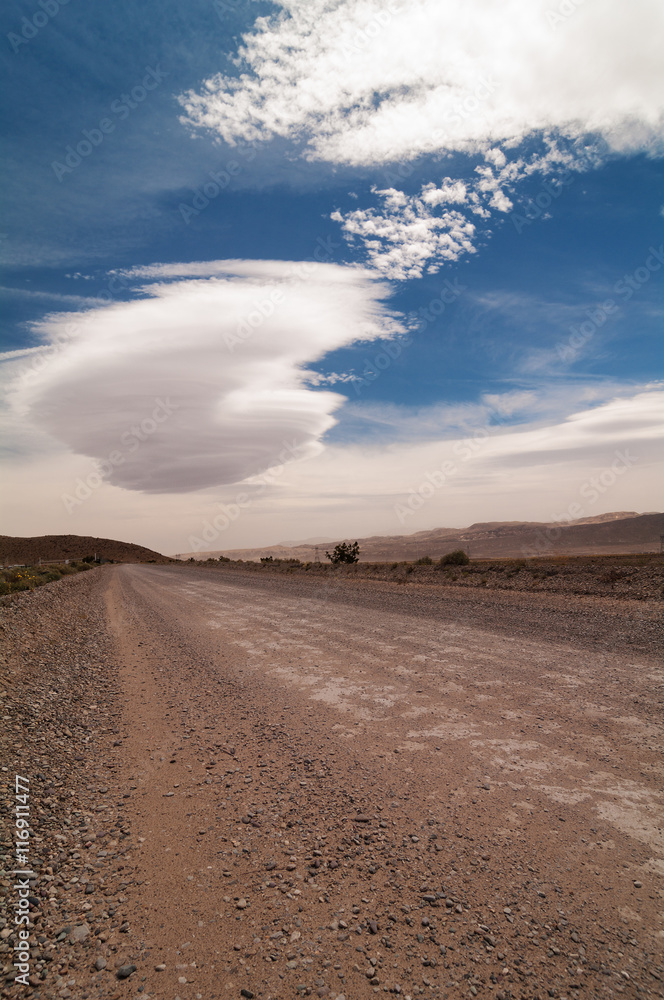 Unpaved road and lenticular clouds in the Mojave desert in California.