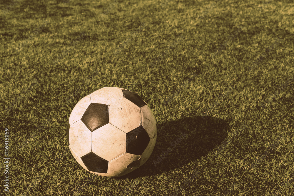 Obraz premium Old soccer ball on green grass, vintage tone