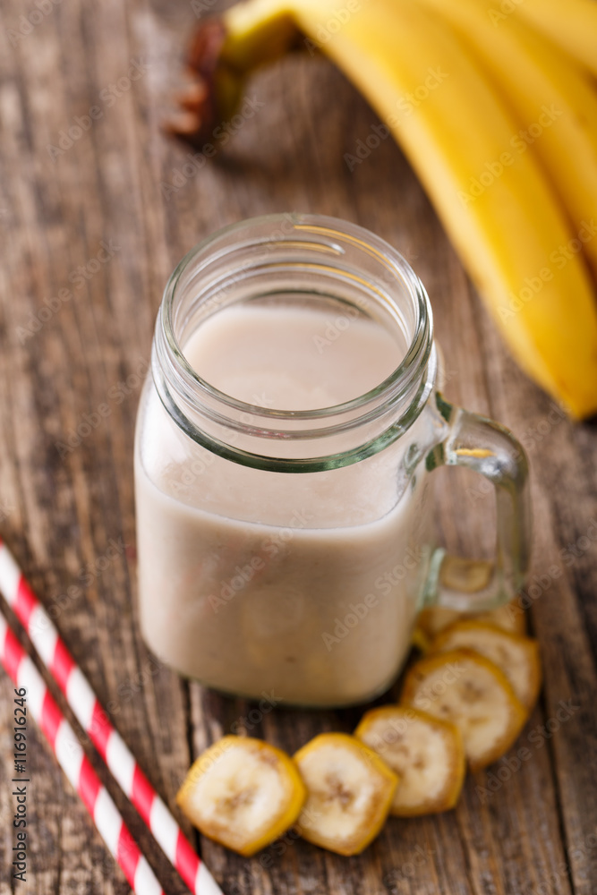 Healthy banana smoothie in glass jar with bananas on wooden tabl Healthy banana smoothie in glass jar with bananas on wooden tabl