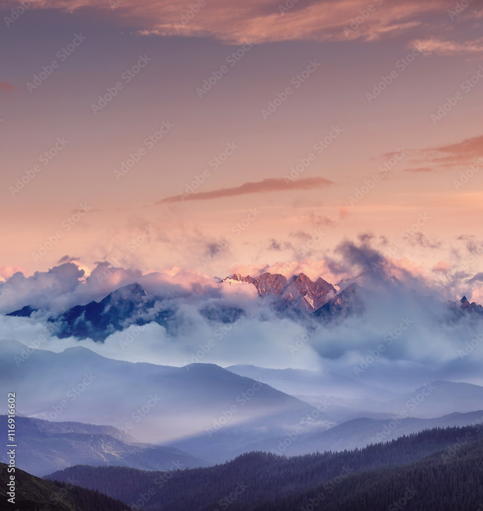 High mountain range in the clouds during sunrise. Beautiful panoramic landscape