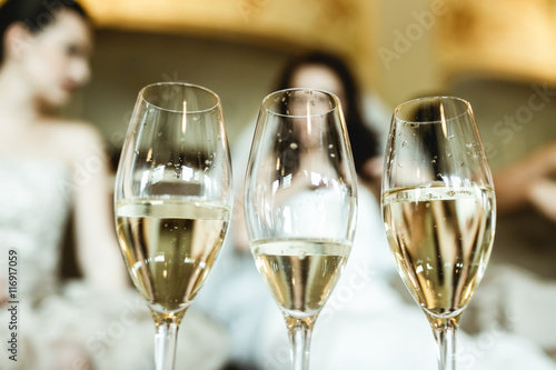 Glasses with champagne stand on the table in the front of bride. photo