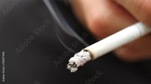 smoldering cigarette in the hand closeup