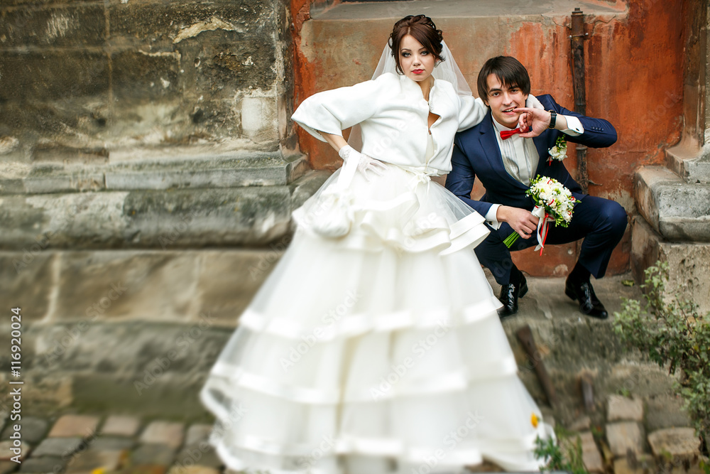 Groom sit squatting on a stone footstep behind a bride Groom sit squatting on a stone footstep behind a bride