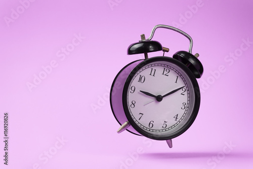 black vintage alarm clock falling on the floor with color backgr