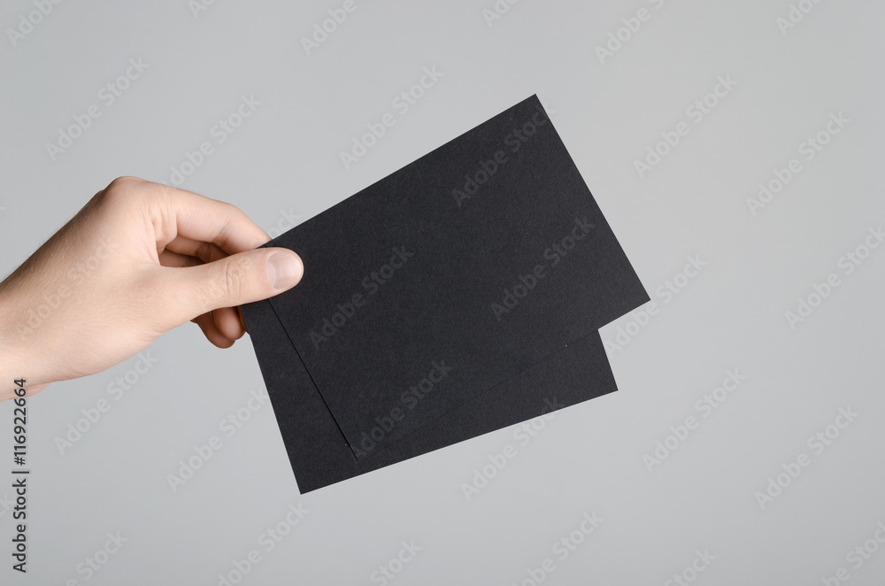 Black A6 Flyer / Postcard / Invitation Mock-Up - Male hands holding black flyers on a gray background. Black A6 Flyer / Postcard / Invitation Mock-Up - Male hands holding black flyers on a gray background.