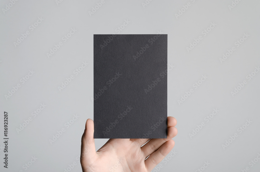 Black A6 Flyer / Postcard / Invitation Mock-Up - Male hands holding a black flyer on a gray background. Black A6 Flyer / Postcard / Invitation Mock-Up - Male hands holding a black flyer on a gray background.