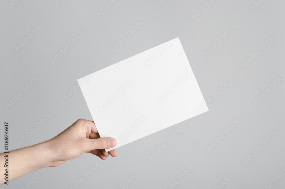 A5 Flyer / Invitation Mock-Up - Male hands holding a blank flyer on a gray background. A5 Flyer / Invitation Mock-Up - Male hands holding a blank flyer on a gray background.