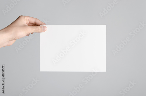 A5 Flyer / Invitation Mock-Up - Male hands holding a blank flyer on a gray background.