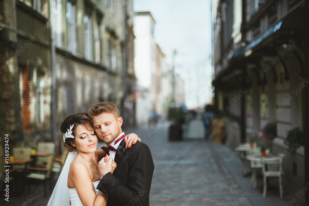 Bride and bridegroom embracing at street
