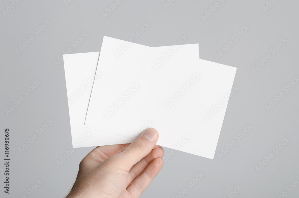 A6 Flyer / Postcard / Invitation Mock-Up - Male hands holding blank flyers on a gray background. A6 Flyer / Postcard / Invitation Mock-Up - Male hands holding blank flyers on a gray background.