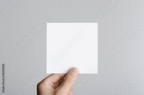 Square Flyer / Invitation Mock-Up - Male hands holding a blank flyer on a gray background.