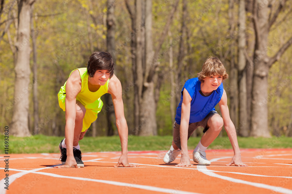 Two teenage boys ready to start running on a track