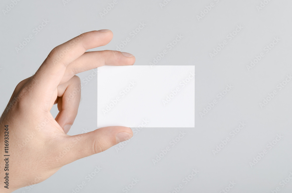 Obraz premium Business Card Mock-Up (85x55mm) - Male hands holding a blank card on a gray background.
