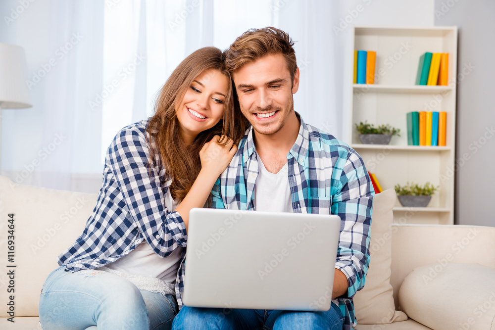 Portrait of happy young family sitting on sofa with laptop Portrait of happy young family sitting on sofa with laptop
