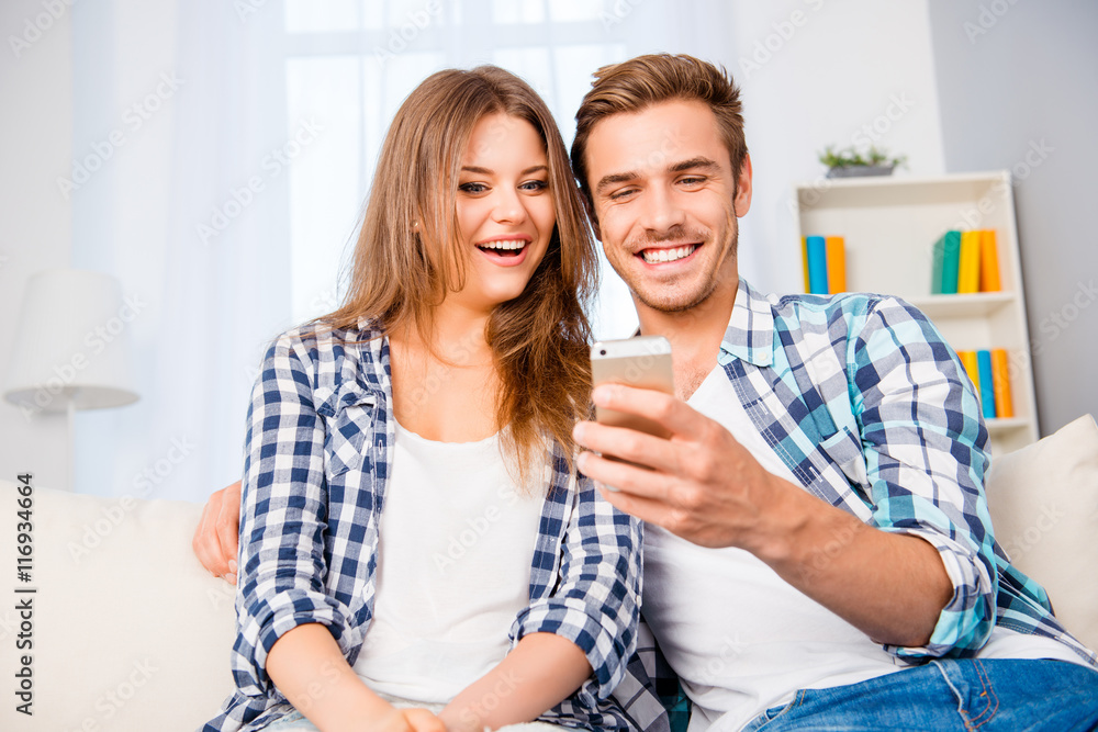 Smiling man showing sms on mobile phone to his excited wife Smiling man showing sms on mobile phone to his excited wife