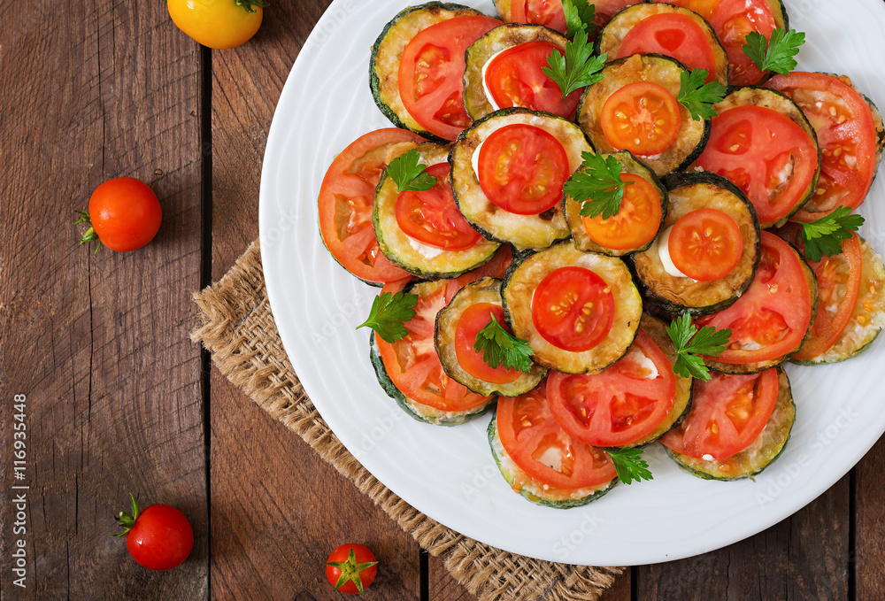 Dish with a snack of fried zucchini with tomatoes. Top view Dish with a snack of fried zucchini with tomatoes. Top view