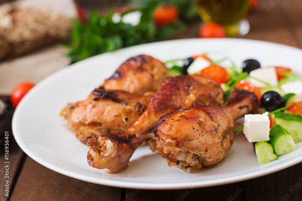 Appetizing oven baked golden chicken drumsticks and Greek salad Appetizing oven baked golden chicken drumsticks and Greek salad