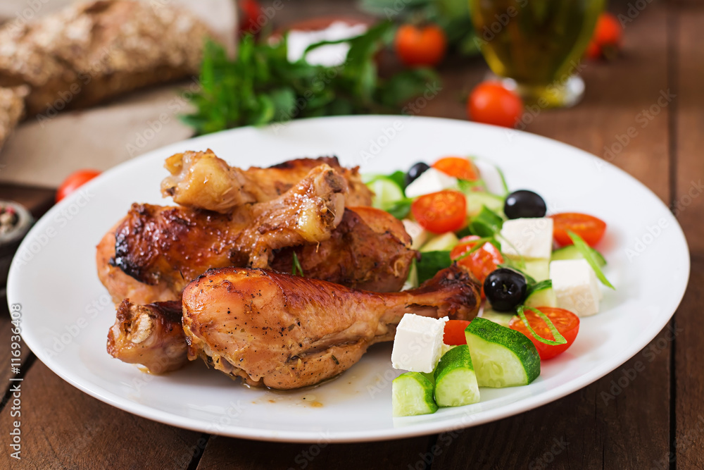 Appetizing oven baked golden chicken drumsticks and Greek salad