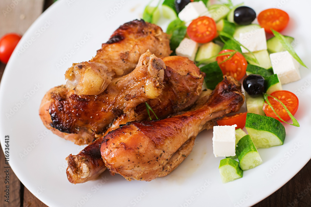 Appetizing oven baked golden chicken drumsticks and Greek salad Appetizing oven baked golden chicken drumsticks and Greek salad