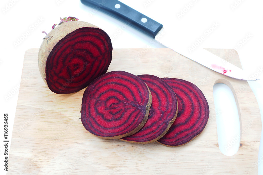 Close up of fresh sliced beetroot on a wooden cutting board.