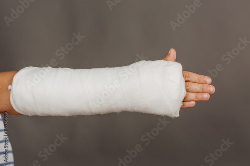 Foto Close-up of a broken arm in a cast on  grey background.  Medicin