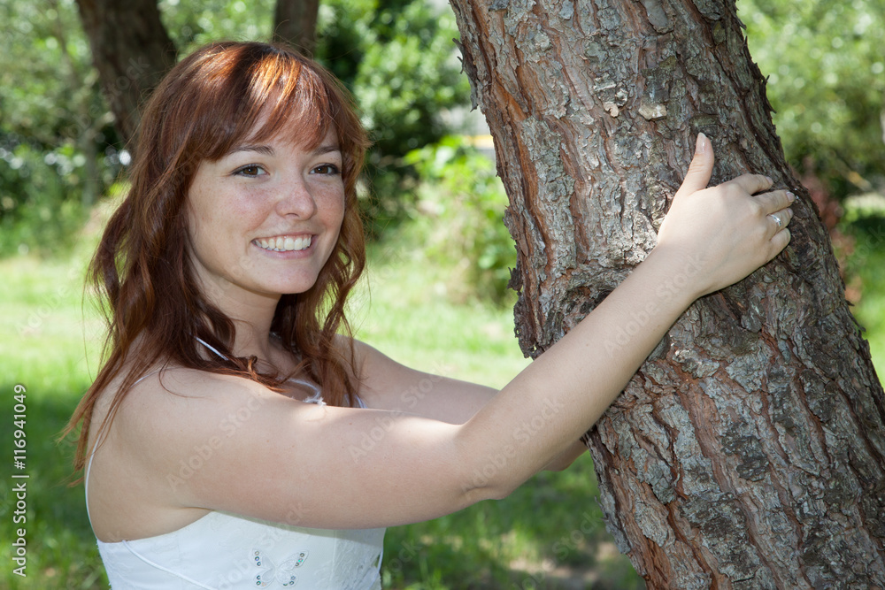Red hair bride in a wedding dress outside holding tree Red hair bride in a wedding dress outside holding tree