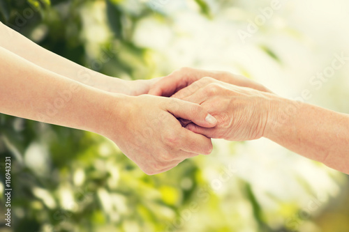 close up of senior and young woman holding hands © Syda Productions