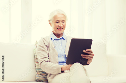 happy senior woman with tablet pc at home