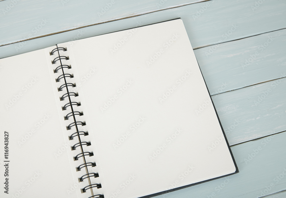 A blank, spiral bound journal on a painted wooden desktop background A blank, spiral bound journal on a painted wooden desktop background