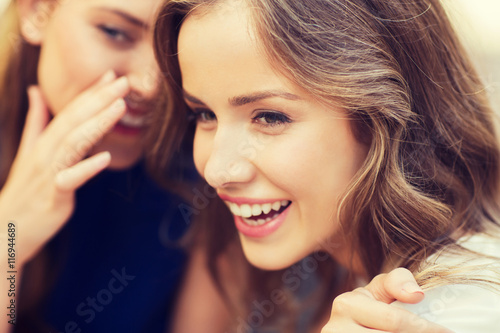 Bild auf Leinwand smiling young women gossiping and whispering