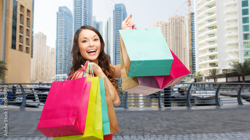 happy woman with shopping bags over dubai city