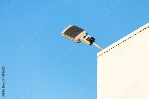 Modern industrial lamp on a building against sky.