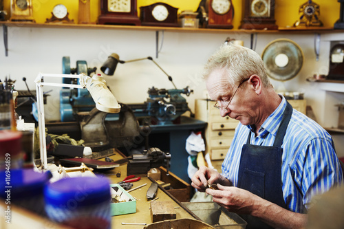 A clock maker busy in his workshop.  photo