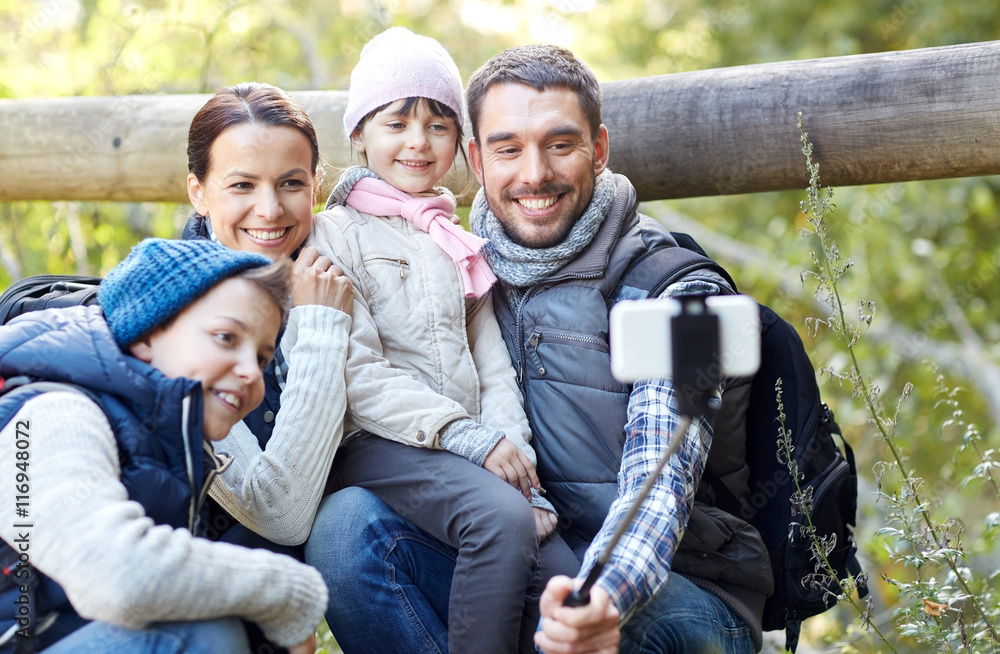 happy family with smartphone selfie stick in woods