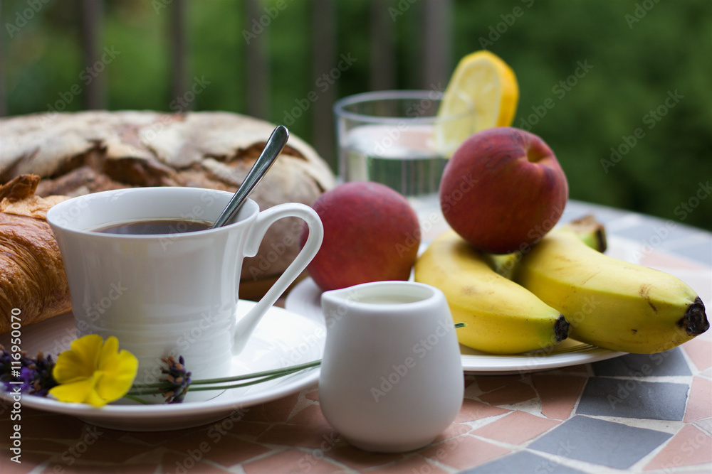 Breakfast with cup of coffee and croissant, bread and fruits in background Breakfast with cup of coffee and croissant, bread and fruits in background