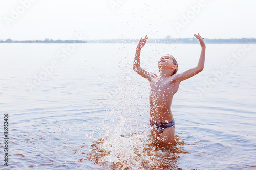 boy enjoys swimming in the river. the child splashing in river. the concept of a happy childhood.