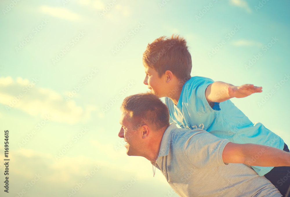Happy father and son having fun over beautiful sky outdoors Happy father and son having fun over beautiful sky outdoors