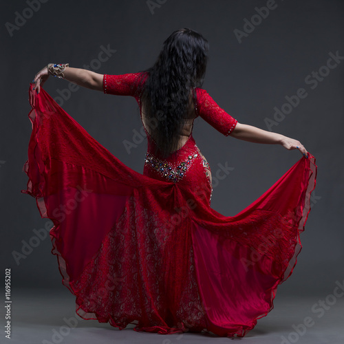 Valokuva Young beautiful exotic eastern women performs belly dance in ethnic red dress wi