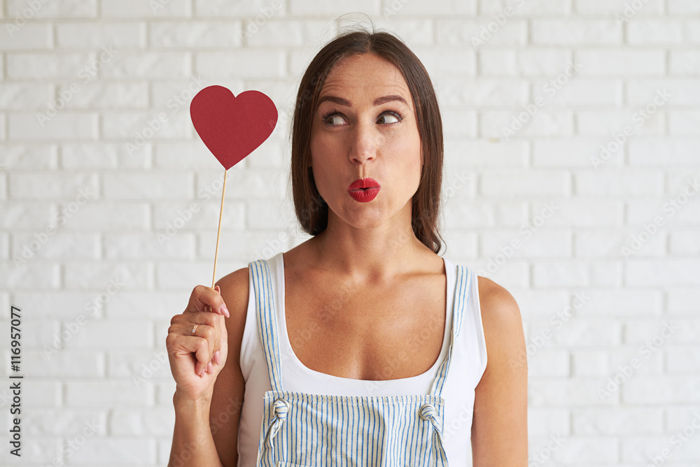 Amazing beautiful woman holding red paper heart and look at it Amazing beautiful woman holding red paper heart and look at it