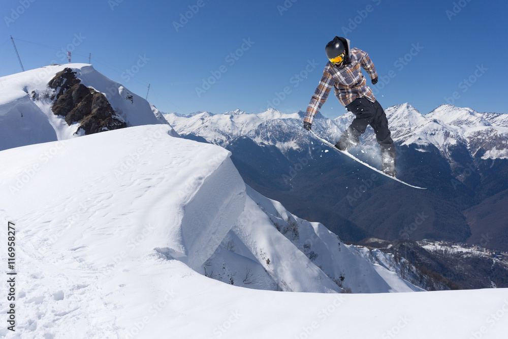 Snowboarder jumps on winter mountain.