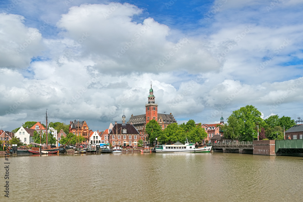 Leer, Germany. View from Leda river on City Hall in Dutch Renaissance style, Old Weigh House in Dutch classical Baroque style, Tourist Harbor with historical boats and Bridge of Erich vom Bruch.