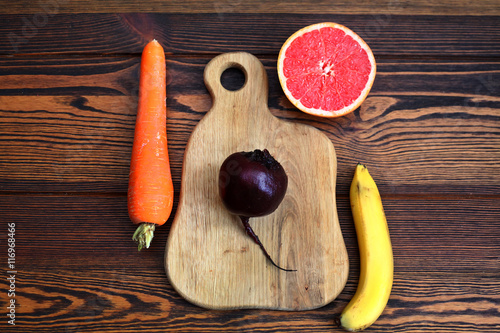 морковь, грейпфрут, свекла, банан на деревянной доске на деревянном столе. Набор фруктов для фруктового сока и смузи