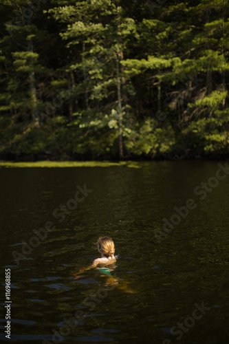 Girl swimming in lake at wood