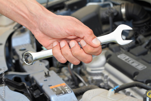 Car service concept, Mechanic Hand Hold Spanner Tool, man checking the condition of car engine.