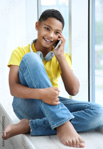 African American boy with headphones and cellphone at home