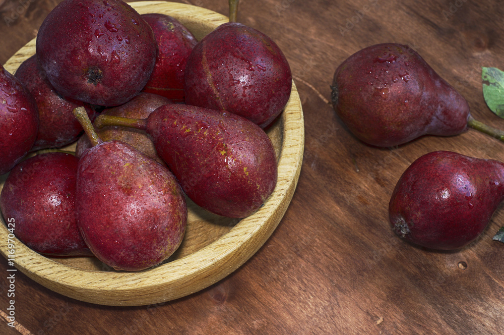 Ripe red pear in a wooden plate Ripe red pear in a wooden plate