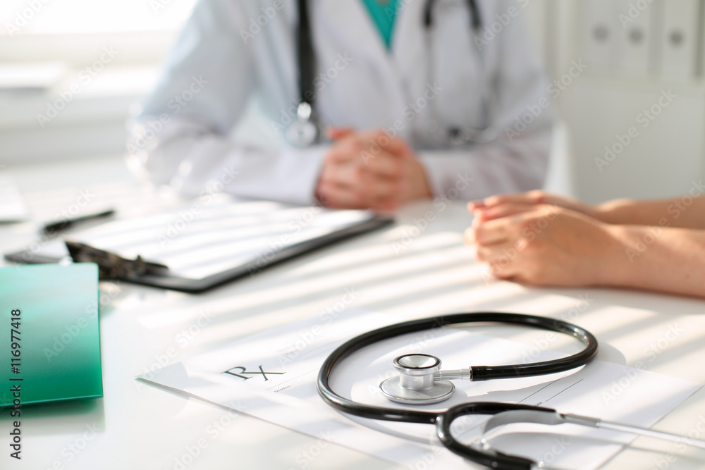 Stethoscope next to hand of doctor reassuring her female patient. Medical ethics and trust concept Stethoscope next to hand of doctor reassuring her female patient. Medical ethics and trust concept
