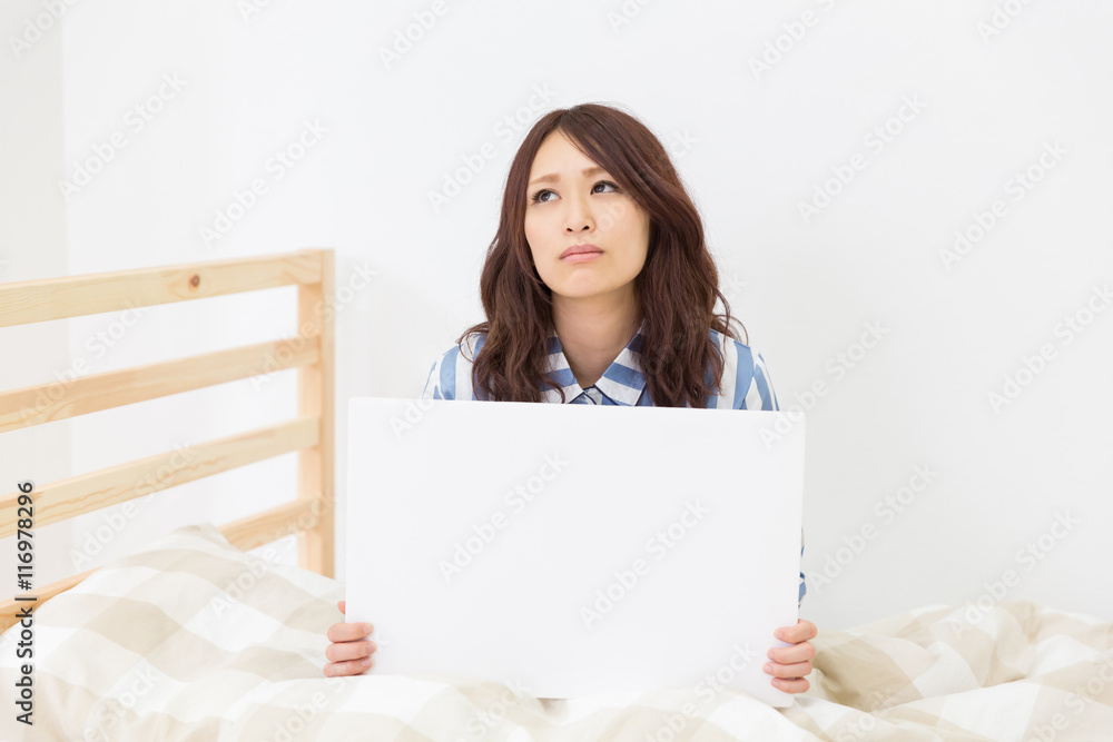 ホワイトボードを持つ女性　パジャマ　考える